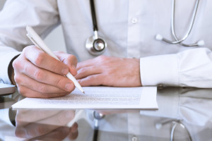 Male doctor writing medical prescription or certificate