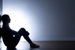 Teenager with depression sitting alone in dark room