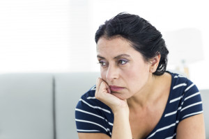 Unhappy woman sitting on the couch on white background