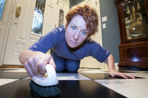 Close up view of a woman scrubbing the floors on her hands and knees.