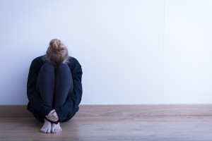 Image of a woman siiting curled up on the ground