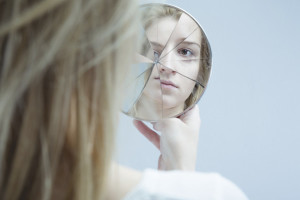 Image of woman with mental disorder holding broken mirror