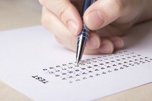 female hand filling test score sheet with metal pen